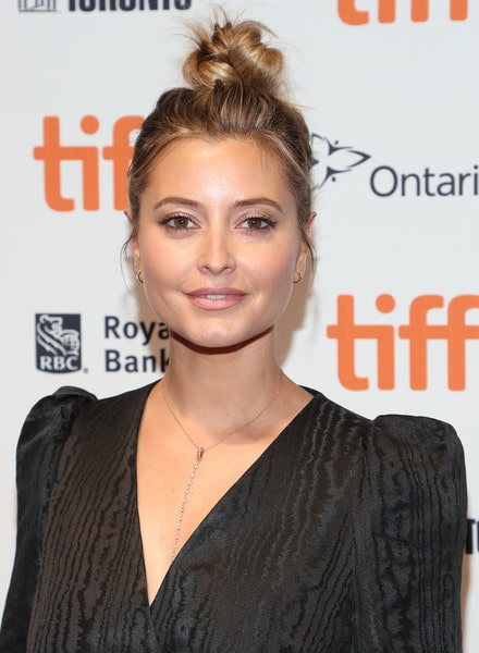 Holly Valance at a recent event with hair tied up to a messy bun wearing black dress with plunged neckline and a minimalistic necklace and soft glam make-up